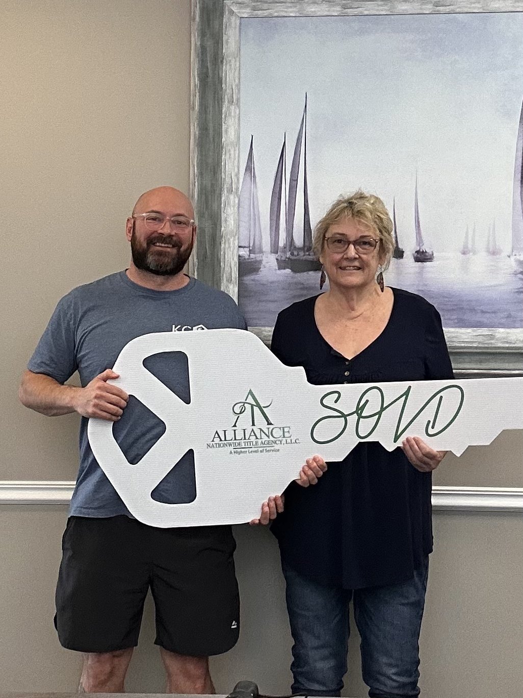 Ash with a happy Kansas City homeowner holding a SOLD key at closing